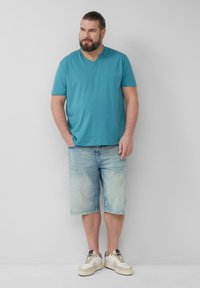 Tealen v-hals t-shirt, licht denim bermuda shorts en witte sneakers met grijze accenten. Gladde textuur, casual pasvorm. Geen zichtbare patronen.