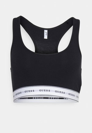 Soutien-gorge de sport noir court en tissu doux. Doté d'un design dos nageur et d'une bande blanche avec le logo "GUESS" en texte noir.
