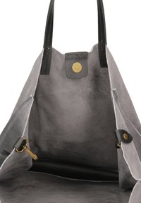 Grijze suede draagtas met zwarte leren accenten, voorzien van een drukknoopsluiting en een binnenzak. Gladde textuur en open ontwerp.