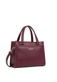 Sac à main en cuir bordeaux avec surface texturée, deux poignées courtes, bandoulière amovible et détail en logo doré à l'avant.