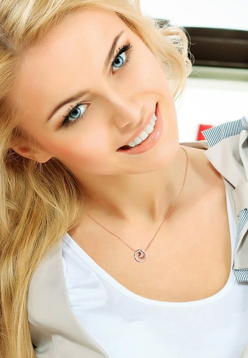 Collier pendentif avec un design circulaire entrelacé, chaîne en or rose et accents argentés. Porté par un mannequin aux longs cheveux blonds et aux yeux bleus.