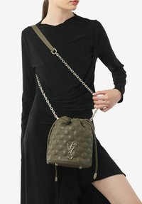 Borsa a secchiello in pelle verde oliva con motivo circolare in rilievo, catena e tracolla regolabile, con logo color oro e chiusura a coulisse.