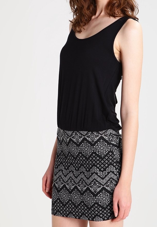 Débardeur noir à encolure dégagée associé à une jupe courte avec un motif géométrique noir et blanc. Tissu doux, design ajusté.