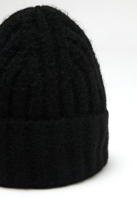 Gorro de punto negro con un diseño texturizado y acanalado. Hecho de lana suave, presenta un dobladillo enrollado para mayor calidez y comodidad.