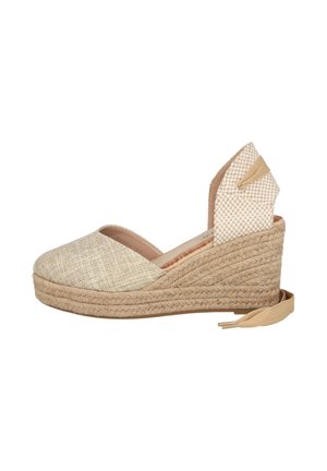Alpargata cuña tejida beige con puntera cerrada, lazada en el tobillo y suela de plataforma con textura de cuerda, vista desde un lateral.