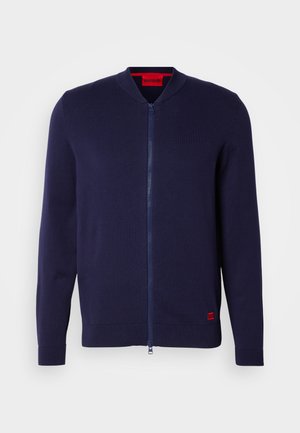 Tumesinine zip-up kardigan, mis on valmistatud kudumiskangast, ümmarguse kaeluse, ribatatud mansettide ja punase logo aktsendiga allääres.