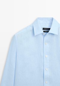 Light blue long-sleeve linen shirt with pointed collar and white buttons, showing upper front and label reading Massimo Dutti.
