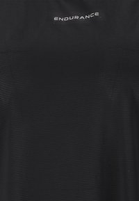 Musta urheilupaita, jossa on teksturoitu kangas, pyöreä kaula-aukko ja valkoinen "ENDURANCE" -logo rintaan. Kevyt muotoilu.