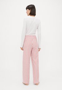Striped wide-leg pants in red and white fabric with a high waistband. Soft texture and loose fit enhance comfort and breathability.