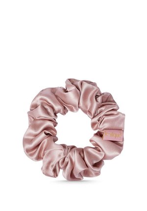 Lichtroze satijnen scrunchie met geplooide stof en een klein rechthoekig merklabel eraan bevestigd.