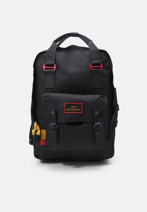 Sac à dos rectangulaire noir avec poche avant, accents rouges sur les bretelles, tirettes de fermeture éclair jaunes et écusson avec le logo Doughnut sur la poche avant.