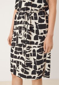 Černobílé vzorované šaty s volným střihem, se staženým pasem a bočními rozparky, vyrobené z lehké látky.