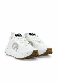 Witte sneakers met een gestructureerde bovenkant, grijze logo-detail en een dikke gespikkelste zool. Bevat een zwart merkembleem op de tong.