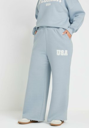 Jogging léger bleu en tissu doux, avec une coupe décontractée, une taille élastique, des poches latérales et un graphique "USA" en blanc sur la jambe.