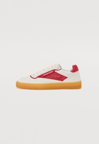 Hvite sneakers med røde detaljer, med en glatt skinn-overdel, perforerte detaljer, gummiersåle og kontrastfarget gummiyttersåle.