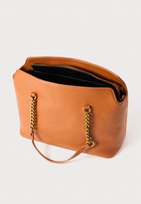 Tan leather tote bag featuring gold chain accents on handles, an open top, and a black lined interior with zippered pocket.
