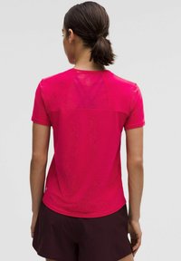 Krátky rukáv športového trička v jasnej ružovej farbe, ktorý má sieťovanú časť na chrbte pre lepšiu priedušnosť, vyrobený z hladkej, ľahkej tkaniny.