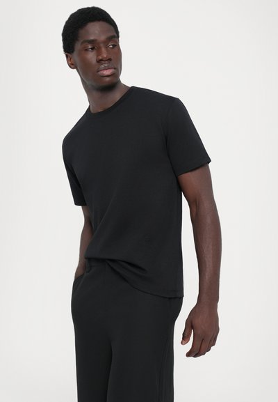Schwarzes Rundhals-T-Shirt aus weichem, leichtem Stoff mit kurzen Ärmeln und lockerer Passform. Minimale Details am Saum.