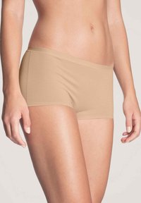 Beige katoenen boxershorts met een naadloos ontwerp, zachte textuur en een lage taille, met een gladde tailleband zonder zichtbare stiksels.