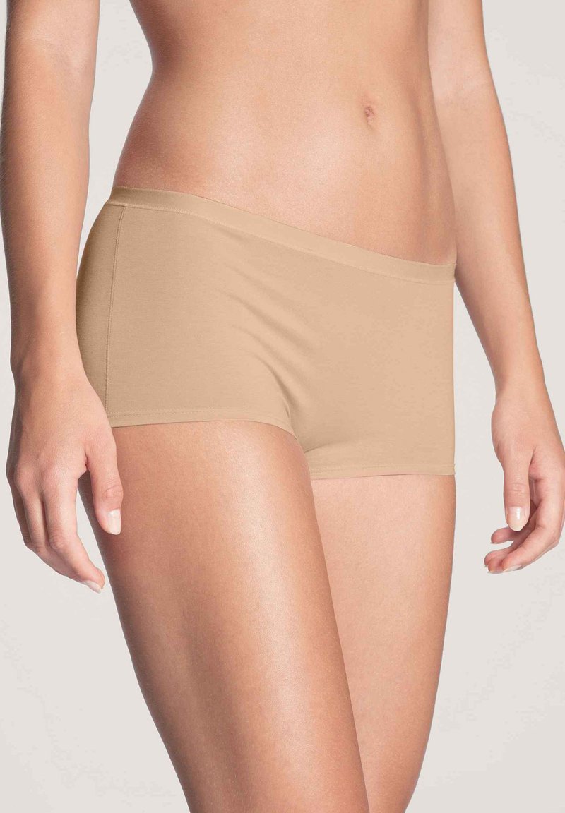 Beige katoenen boxershorts met een naadloos ontwerp, zachte textuur en een lage taille, met een gladde tailleband zonder zichtbare stiksels.