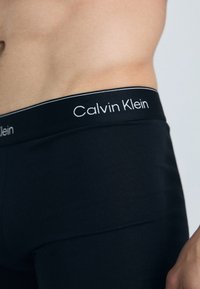 Schwarze Baumwoll-Boxershorts mit einem weichen Bund, der "Calvin Klein" in Weiß trägt. Das Material ist glatt und enganliegend.