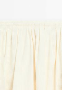 Cream fabric with fine vertical pinstripes gathered at the top with an elastic waistband.