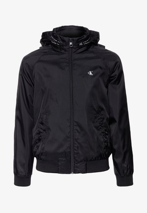 Černá zipová bunda s kapucí, vyrobená z hladkého, lehkého materiálu. Obsahuje elastické manžety a pas, s logem na hrudi a výstřihu.