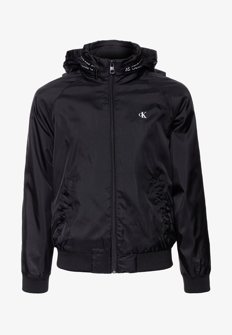 Černá zipová bunda s kapucí, vyrobená z hladkého, lehkého materiálu. Obsahuje elastické manžety a pas, s logem na hrudi a výstřihu.