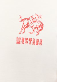 T-shirt en coton blanc avec un graphique rouge représentant un cavalier sur un cheval indompté, avec le mot "MUSTANG" en dessous, dans un style audacieux et usé.