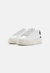 Sneakers bianchi con tomaia in pelle liscia, caratterizzati da dettagli neri e lacci stampati. Suola spessa e testurizzata per un comfort migliore.