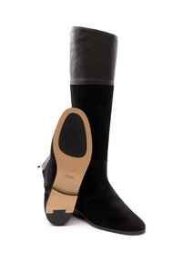 Schwarze Wildleder-Stiefel in Knielänge mit einem glatten Lederoberteil, spitzem Zehenbereich und einer strukturierten Seitenpartie. Die Sohle ist hellbraun mit schwarzen Akzenten.