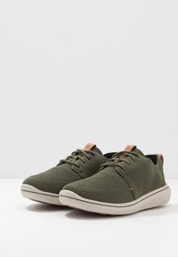 Sneaker verde oliva con tomaia in rete, punta rotonda, design con lacci e dettaglio beige sul tallone, dotate di suola in gomma bianca.