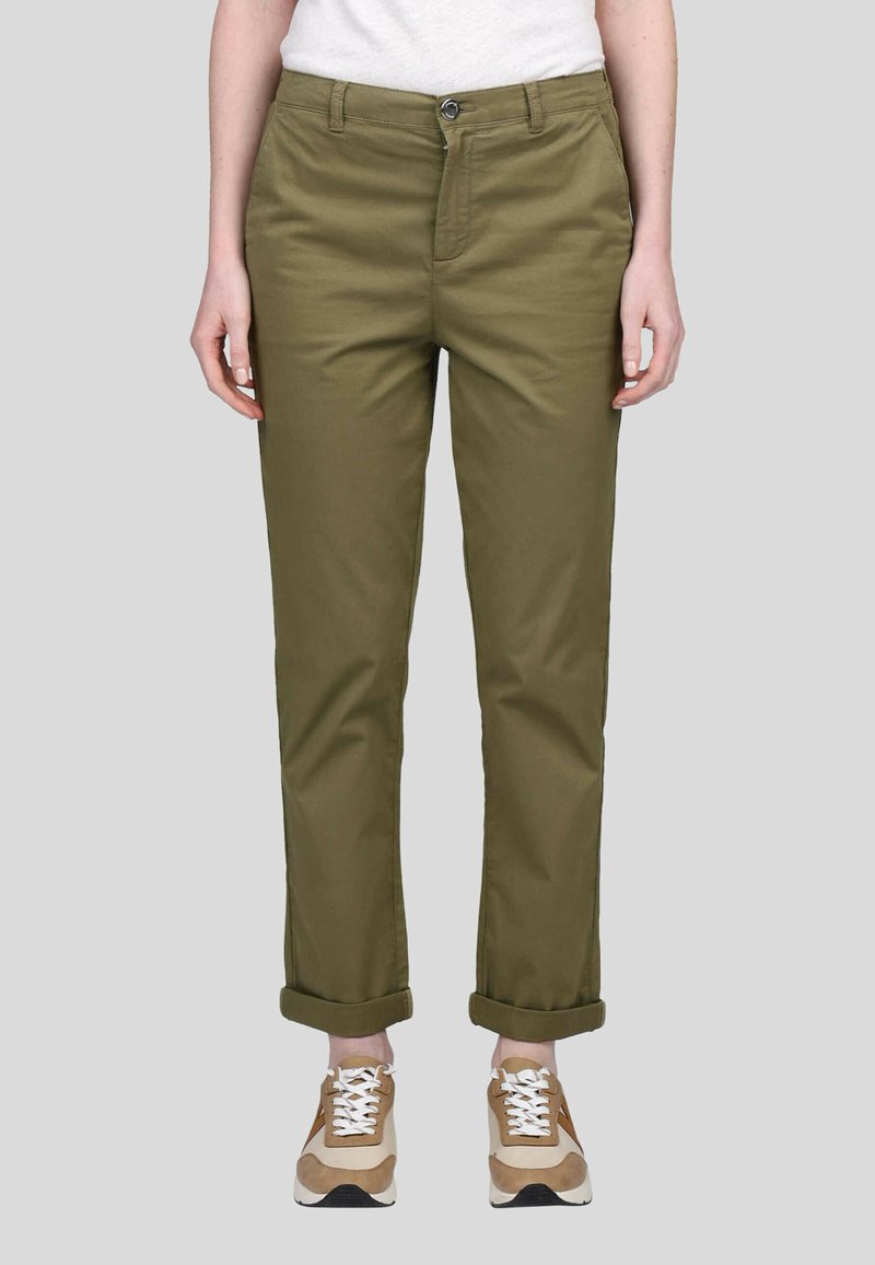 Chinos vert olive avec une coupe droite, fabriqués en coton, dotés de bas de pantalon retroussés et d'une fermeture à bouton, associés à des baskets beiges.
