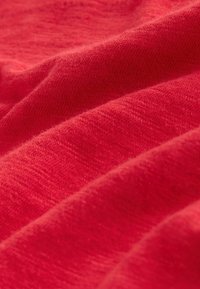 Tissu rouge doux avec une texture fine en maille, présentant de délicates plis et des ombrages subtils sur toute la surface.