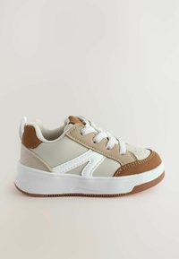 Baskets basses avec un dessus beige et blanc, accents en daim marron, bout rond, semelle en caoutchouc et lacets blancs. Surface texturée et détails de couture.