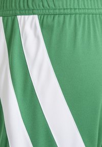 Green fabric with white diagonal stripes and elastic waistband, showing close-up textile texture and stitching details.