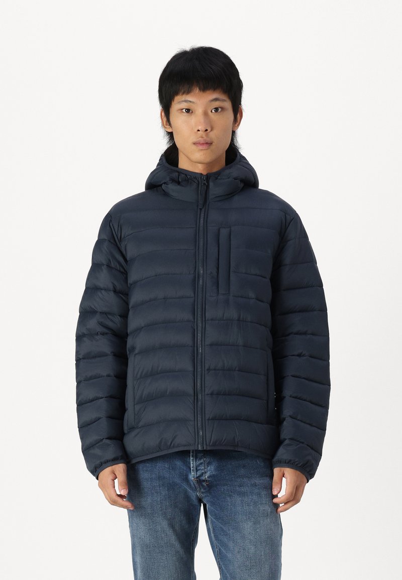 Mørkeblå polstret jakke med glidelås foran, fast hette og brystlomme. Har kviltet tekstur og elastiske ermer.