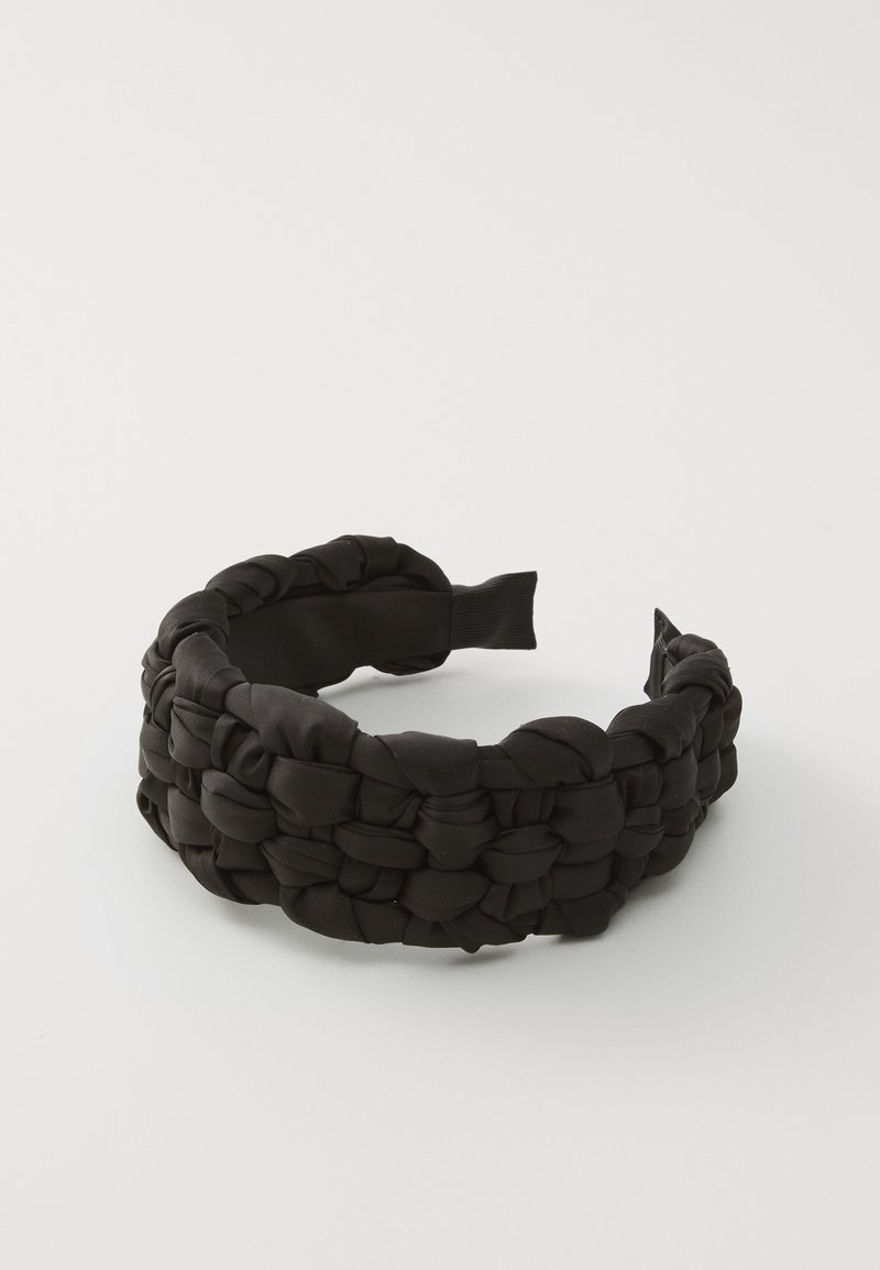 Černý textilní čelenka s pleteným designem a měkkým, texturovaným povrchem. Zadní část má elastický pás pro nastavitelnou velikost.