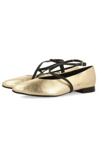 Bailarinas metálicas doradas con un acabado texturizado, punta afilada y tiras cruzadas negras. Tacón bajo y diseño minimalista para un uso versátil.