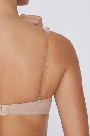 Béžová podprsenka s průhlednými nastavovacími ramínky, s měkkou texturou a zapínáním na háček a oko. Detailní pohled zezadu ukazuje hladké kontury.