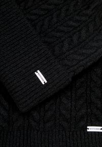 Czarny dziany szalik z wzorem warkocza, miękką teksturą i tkanią metką z logo „WITTCHEN”, kontrastującą z tkaniną.