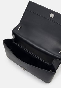 Bolso de mano de cuero negro con una textura suave, en forma rectangular y con herrajes plateados. Presenta un cierre magnético y un interior espacioso.