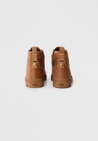 Botas de tobillo de cuero marrón con una suela de goma resistente, cremallera lateral, lengüeta de tela y logotipo en relieve en el talón.