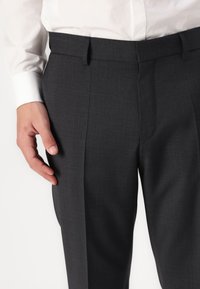 Sötétszürke, szabott nadrág textúrált felülettel, slim fit fazonban, oldalsó zsebekkel és sík elülső derékkal.