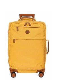 Valise souple jaune avec poignées en cuir, plusieurs poches zippées et quatre roues pivotantes vue de face sur fond blanc.