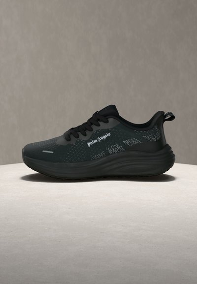 Μαύρο αθλητικό παπούτσι με παχιά σόλα, μαύρα κορδόνια, σήμα "palm angels" στο πλάι και ανώτερο μέρος από διχτυωτό υλικό με σχέδιο, παρουσιάζεται σε ουδέτερο φόντο.