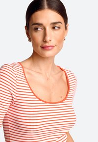 Red and white striped fitted top with a scoop neckline and short sleeves, textured ribbed fabric, accented by a solid red trim.