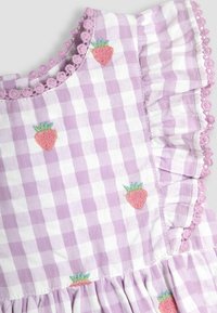 Violetinė ir balta langeline suknelė su raukšlėmis rankovėmis, siuvinėtomis braškėmis ir pompomų apvadu prie kaklo. Minkšta medvilninė medžiaga.