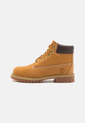 Kohvapea nahast ankle boot pruunist polsterdatud kraega, kuldsete silmadega ja valgete õmblustega. Omab kummist tallat, millel on sooneline muster.