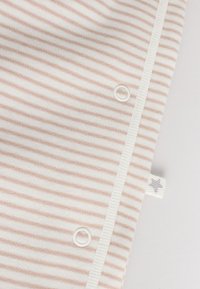 Soft fabric with thin beige and white horizontal stripes, featuring two white snap buttons and a small fabric tag with a gray star.